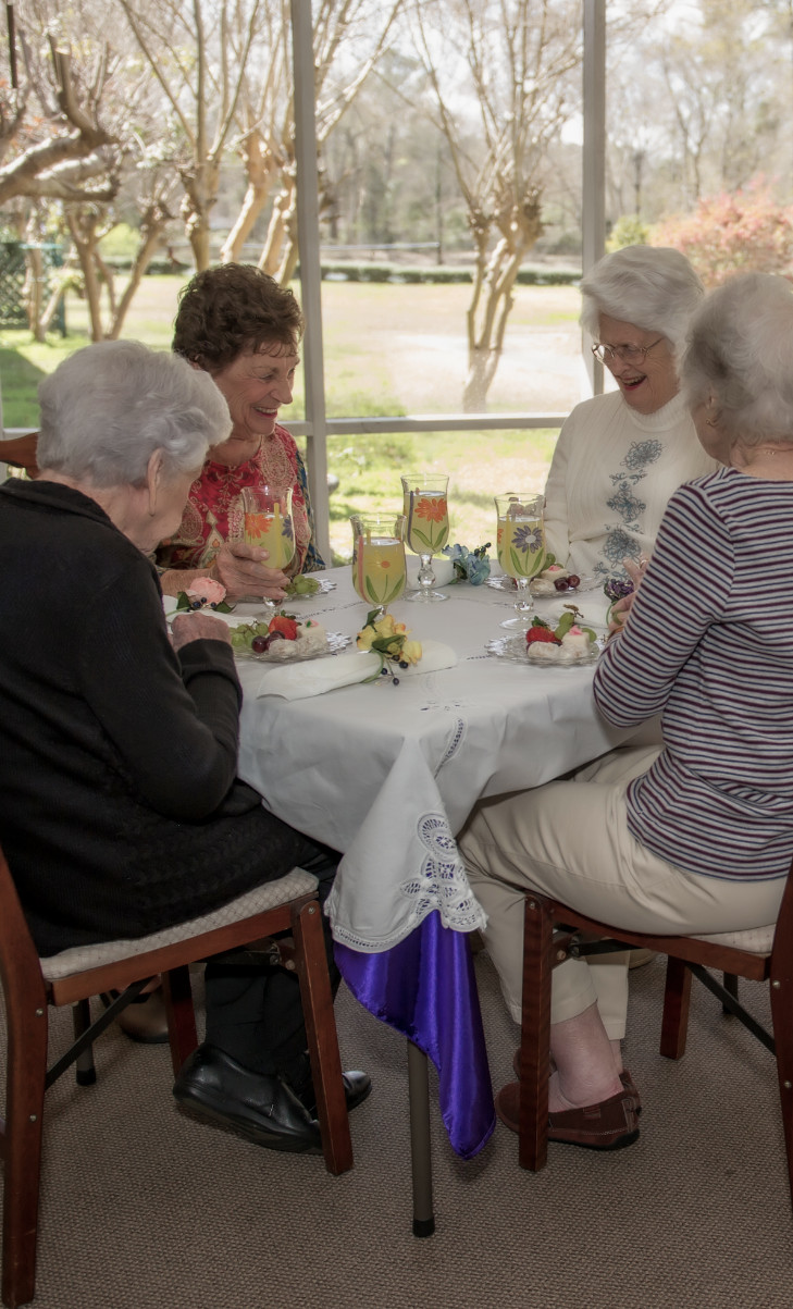 Paved walk through grass with stone table and seats under an umbrella in the sun